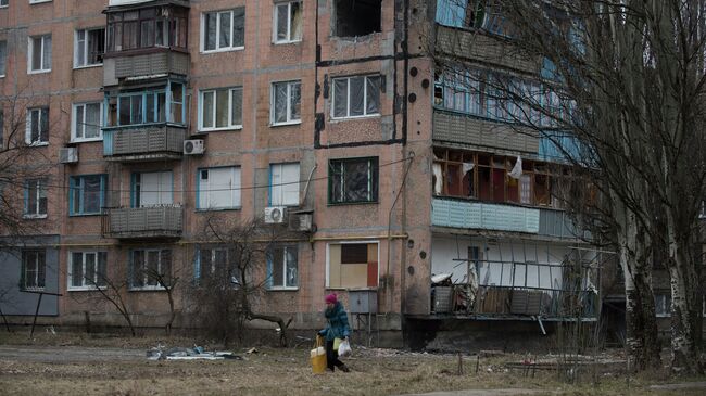 Женщина проходит мимо разрушенного жилого дома в Авдеевке, Архивное фото