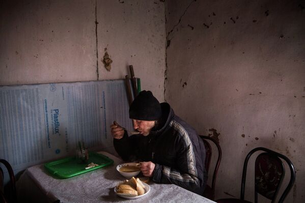 Мужчина ест суп в столовой для нуждающихся в Углегорске, Украина