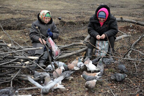 Пожилые женщины кормят голубей на одной из улиц в Дебальцево, Украина