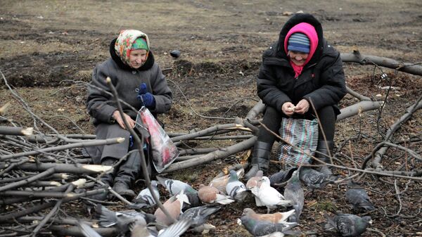 Пожилые женщины кормят голубей на одной из улиц в Дебальцево, Украина