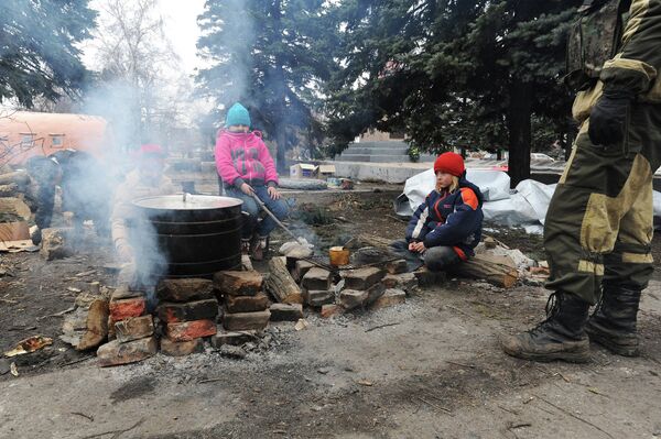Дети греются возле огня, разведенного для приготовления пищи на центральной площади в Дебальцево, Украина