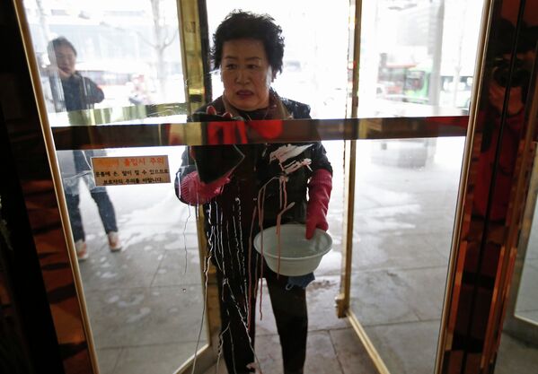 Женщина удаляет пятна крови после нападения на посла США в Южной Корее Марка Липперта