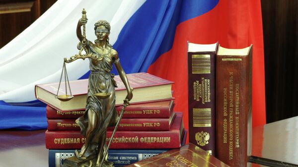 Статуя Фемиды и юридическая литература на столе в зале судебных заседаний. Архивное фото