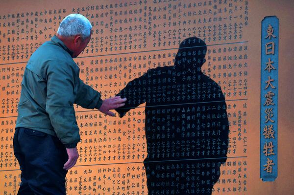 Мужчина у мемориала с именами погибших во время цунами 2011 года. Сендай, Япония. Март 2015 год