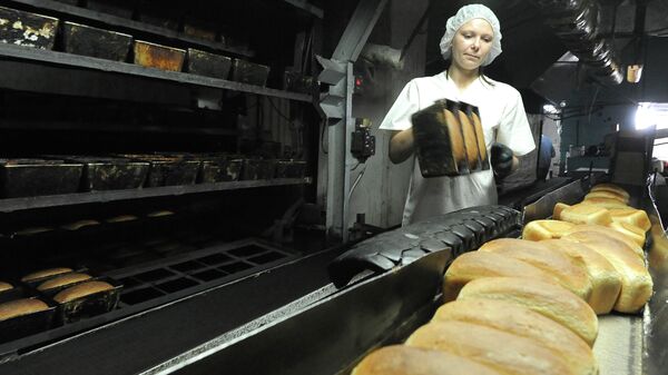 Работница вынимает из формы готовый хлеб. Архивное фото