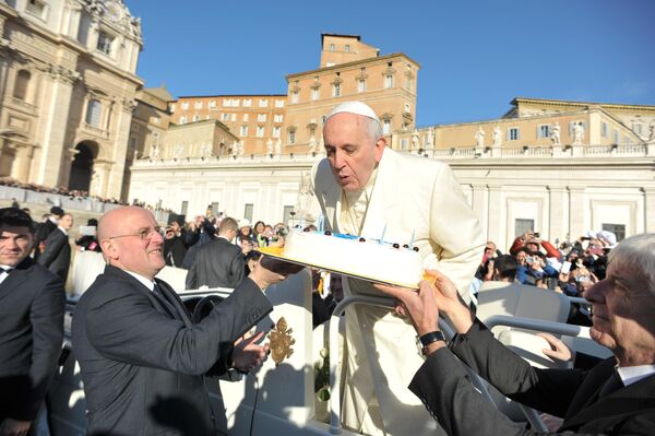 Папа Римский Франциск задувает свечи на праздничном торте на площади Святого Петра в Ватикане