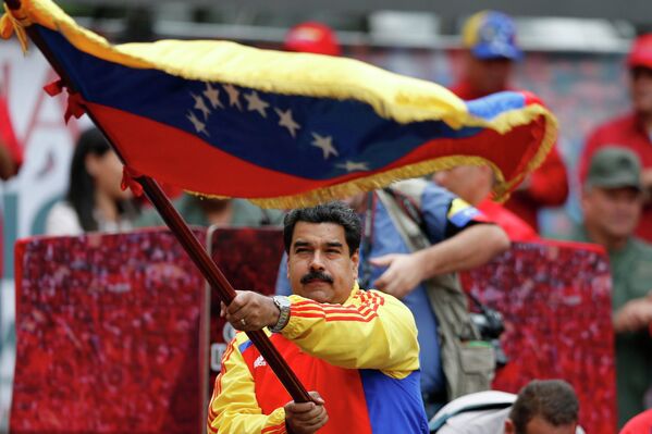 Президент Венесуэлы Николас Мадуро с государственным флагом во время про-правительственной демонстрации неподалеку от президентского дворца в Каракасе. 15 марта 2015