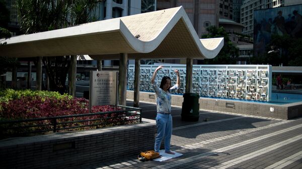 Женщина занимается гинастикой на одной из улиц района Central в Гонконге