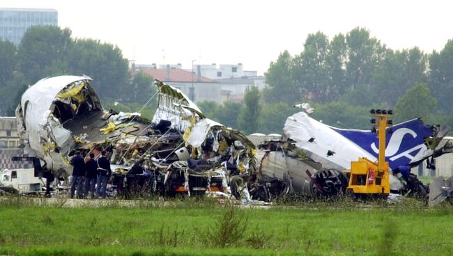 Полицейские на месте столкновения пассажирского самолета MD-87 авиакомпании SAS и легкомоторного частного самолета Cessna 525A в аэропорту Милана, Италия. 9 октября 2001. Архивное фото