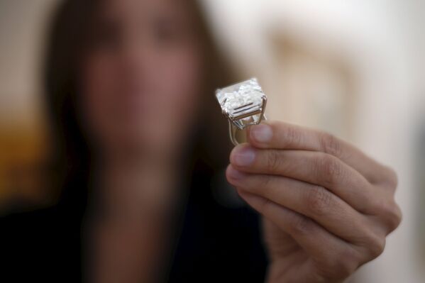 Женщина показывает кольцо с редким бриллиантом изумрудной огранки, весом в 100,2 карата, на предпоказе аукциона Sotheby's 25 марта 2015, Лос-Анджелес