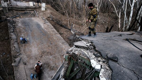 Ополченцы помогают житилям пересечь поврежденный мост в ЛНР. Архивное фото