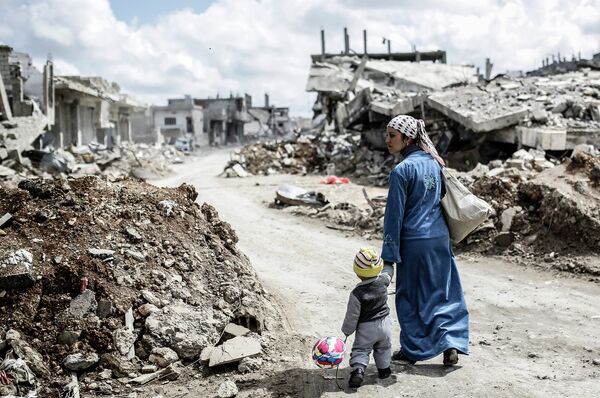 Женщина с ребенком в городе Кобани. Сирия, март 2015