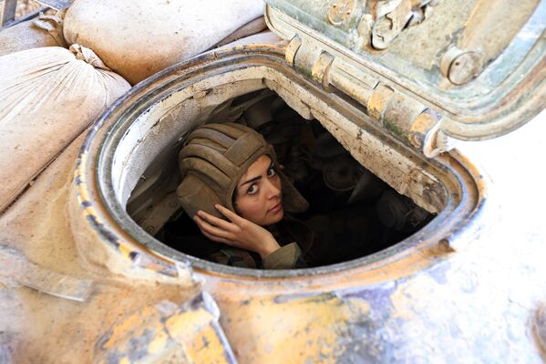 Женщина-военный сирийской армии управляет танком во время столкновений в восточной части Дамаска