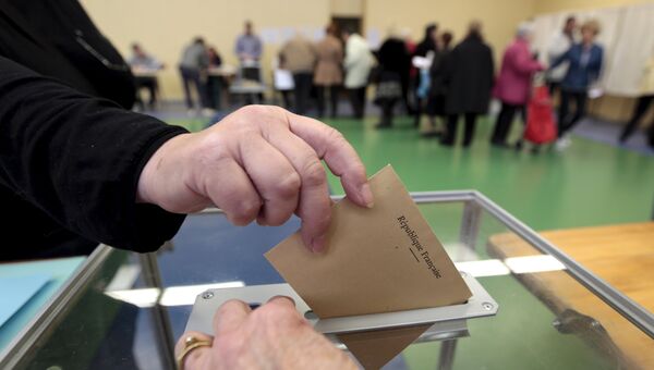 Женщина бросает свой бюллетень на избирательном участке во время департаментских выборов в Ницце, Франция
