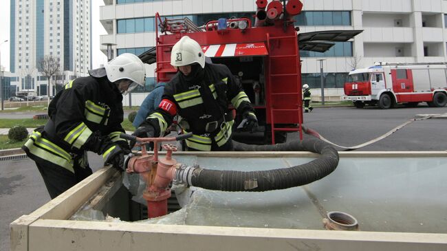 Сотрудники МЧС РФ подключают пожарный рукав к гидранту во время учений
