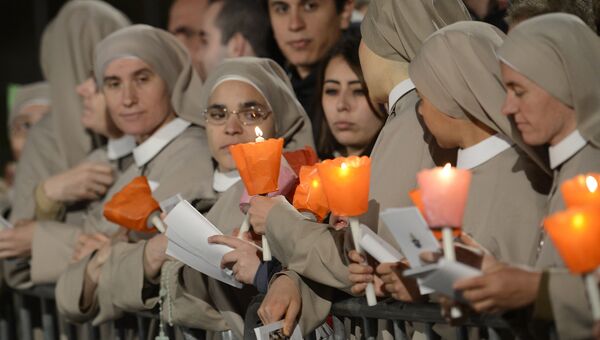 Монахини держат свечи во время празднования Крестного пути в Страстную пятницу в Риме. Архивное фото