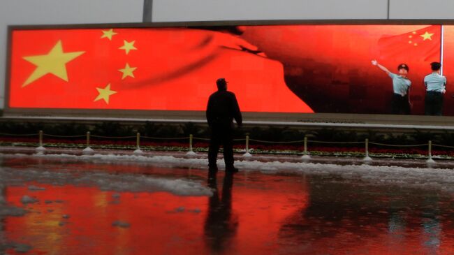 Человек на фоне экрана с флагом Китая. Архивное фото