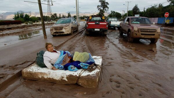 Женщина на матрасе на одной из улиц города Копиапо в Чили во время наводнения. Архивное фото