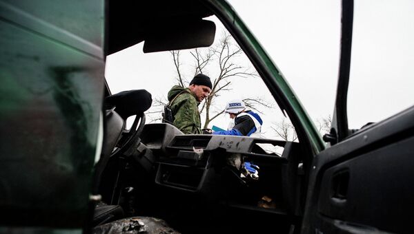 Ополченец ДНР и наблюдатель ОБСЕ возле уничтоженной в результате обстрела машины. Архивное фото