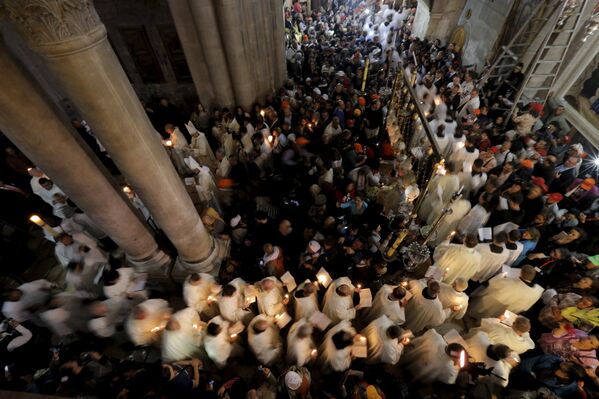 Члены католического духовенства держат свечи во время Пасхального шествия в Храме Гроба Господня в Иерусалиме