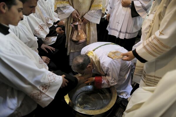 Патриарх Иерусалима моет ноги священника во время католической церемонии в церкви Гроба Господня