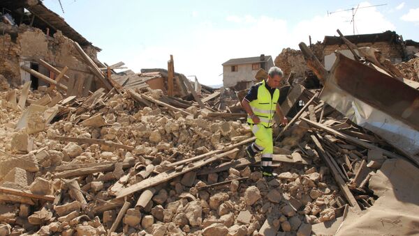 Спасатель на месте разрушенного в результате землетрясения дома в Аквиле, Италия. Архивное фото