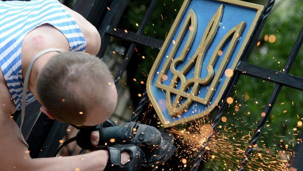 Боец ополчения Луганской народной республики срезает герб Украины с ворот здания областной администрации в Луганске. Архивное фото