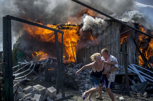 Местные жители спасаются от пожара, возникшего в результате авиационного удара вооруженных сил Украины по станице Луганская, 2 июля 2014