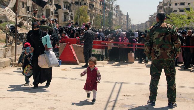 Жительница лагеря Ярмук с детьми покидает опасную зону на окраине Дамаска