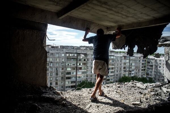 Мужчина осматривает повреждения в жилом доме, пострадавшем от артиллерийского обстрела квартала Мирный в Луганске, 14 июля 2014
