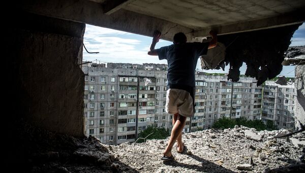 Мужчина осматривает повреждения в жилом доме, пострадавшем от артиллерийского обстрела квартала Мирный в Луганске, Архивное фото