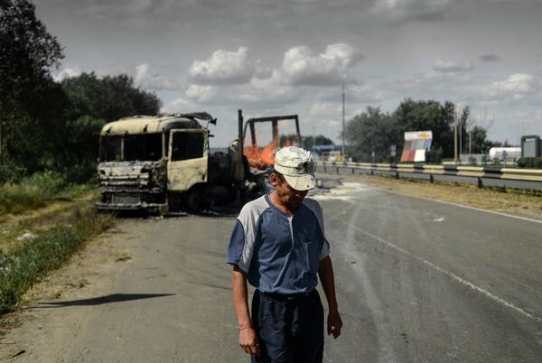 Мужчина у горящего грузовика на окраине Луганска после артиллерийского обстрела поселка Металлист