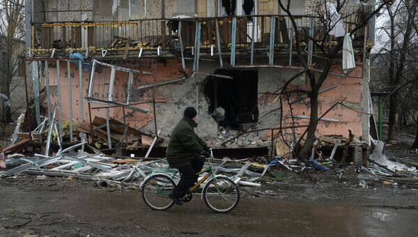 Житель города Дебальцево едет на велосипеде мимо разрушенного в результате обстрелов во время боевых действий жилого дома. Архивное фото