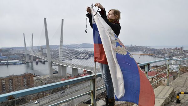 Девушка повязывает траурную ленту на российском флаге во Владивостоке
