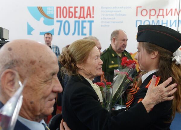 Курсантка военного училища дарит цветы ветеранам во время Всероссийского единого урока Победы