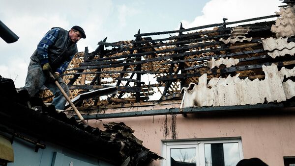 Мужчина убирает мусор с крыши дома, который подвергся обстрелу. Донецк, Украина. Архивное фото