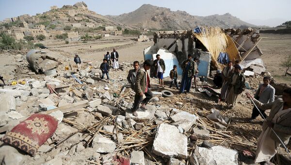 Люди у обломков здания, разрушенного в результате авиаудара к западу от столицы Йемена. Апрель 2015