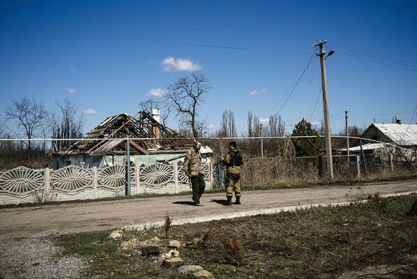 Ополченцы ДНР на фоне разрушенных построек в поселке Спартак в Донецкой области