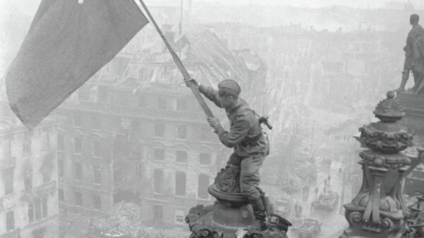 Боец водружает знамя Победы на крыше здания в Берлине