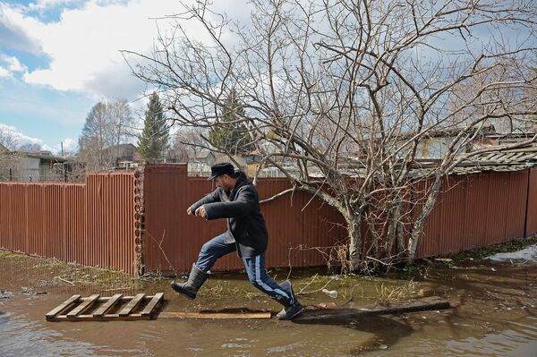 Местный житель проходит по улице дачного поселка, подтопленного талыми водами в результате прорыва дамбы на малой реке Тула под Новосибирском