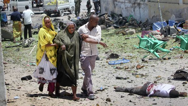 Люди недалеко от места взрыва у ворот административного комплекса в столице Сомали Могадишо. 14 апреля 2015
