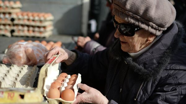 Пенсионерка покупает яйца на городской продовольственной ярмарке в Новосибирске