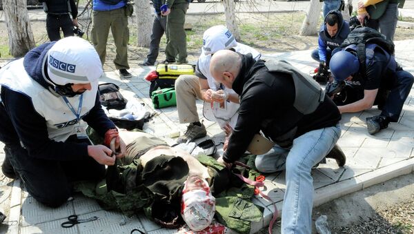 Сотрудники миссии ОБСЕ оказывают первую помощь репортеру телеканала Звезда Андрею Луневу. Архивное фото