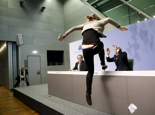 Активистка забралась на стол председателя Европейского центрального банка Марио Драги во время пресс-конференции во Франкфурте, Германия