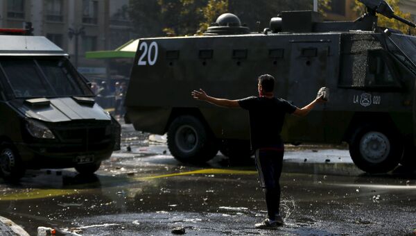 Протестующий в Чили держит камень во время столкновений с органами правопорядка