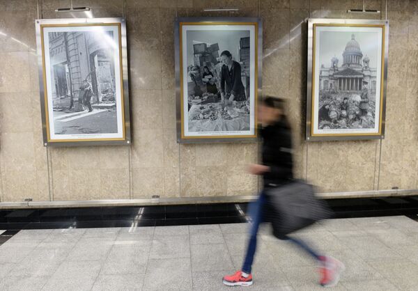 Пассажирка Московского метрополитена рядом с архивными фотоснимками, сделанных во время ВОВ корреспондентами Совинформбюро