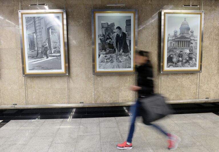 Пассажирка Московского метрополитена рядом с архивными фотоснимками, сделанных во время ВОВ корреспондентами Совинформбюро