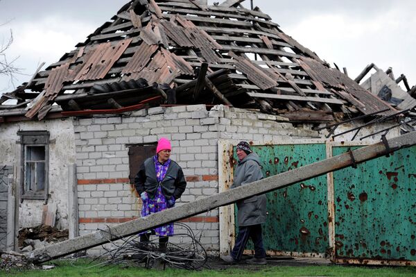 Жительницы поселка Никишино рядом с пострадавшим в результате обстрелов домом