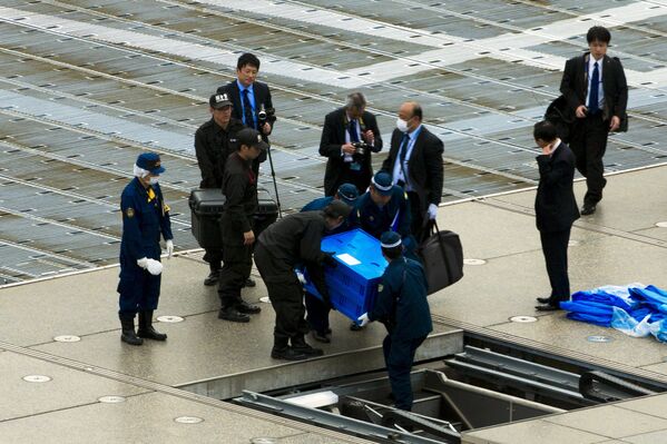Полицейские выносят ящик с беспиолотником с крыши резиденции премьер-министра Японии Синдзо Абэ в Токио