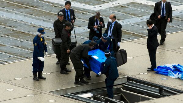 Полицейские выносят ящик с беспиолотником с крыши резиденции премьер-министра Японии Синдзо Абэ в Токио